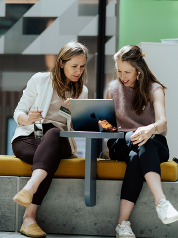 Zwei Frauen arbeiten gemeinsam an einem Laptop beim Bechtle AI Experience Day