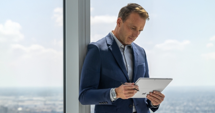 Mann steht vor einem Fenster mit Microsoft Surface Tablet