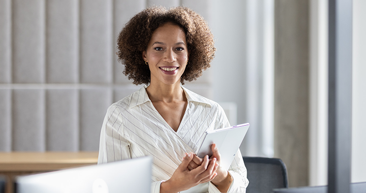 A woman is holding a laptop and smiling