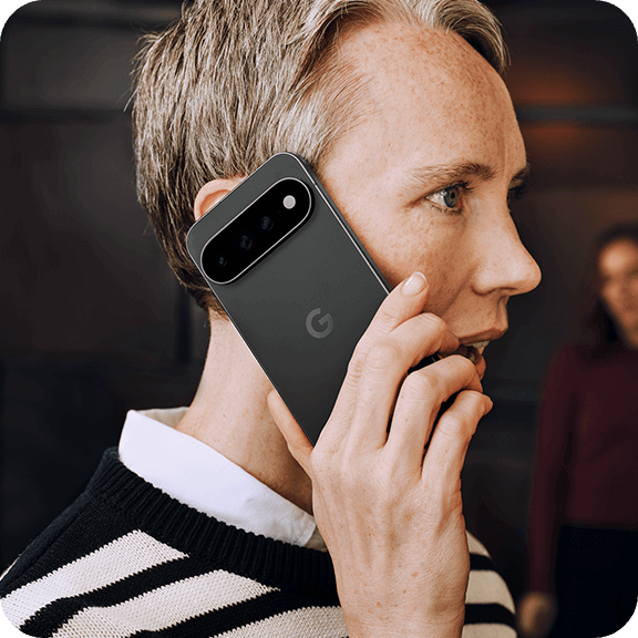 Person hält Smartphone mit Kameramodul am Ohr und führt ein Telefongespräch in moderner Umgebung