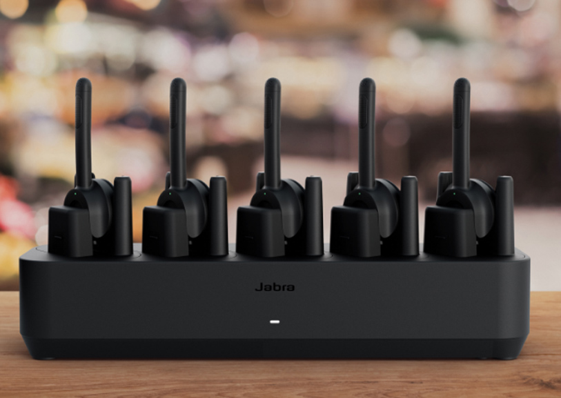 Fünf schwarze Jabra Perform 55Headsets mit Mikrofonarm in einer gemeinsamen Ladestation.