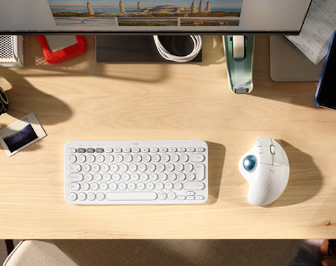 Modern workspace with keyboard and ergonomic trackball mouse on light wooden desk