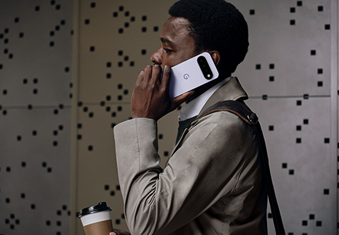 Person in business attire talking on the phone while holding a coffee to go cup on the go