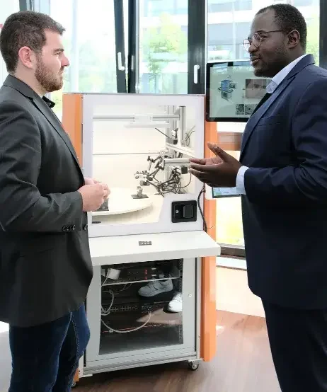 Ein Besucher und ein Experte unterhalten sich an einem Messestand.