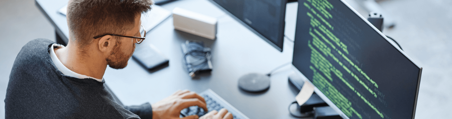 Een man typt op een computertoetsenbord, geconcentreerd op het scherm voor hem.