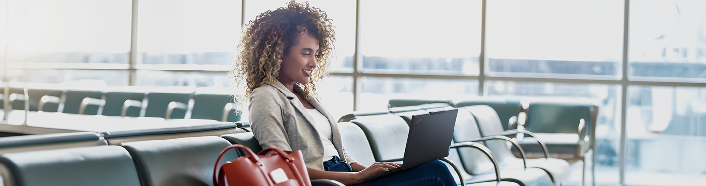 Eine Frau arbeitet in einem Flughafen-Warteraum an einem Laptop.