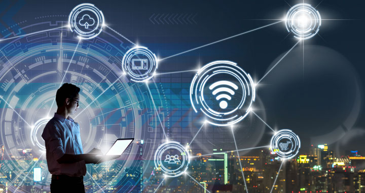 Man using a laptop, with digital icons over a cityscape 