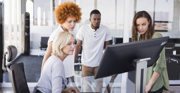 Team collaborating in front of large monitor in office