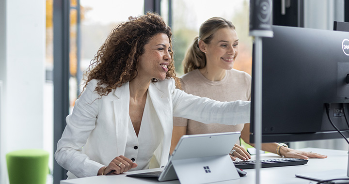 two woman discussing while looking at the same computer screen
