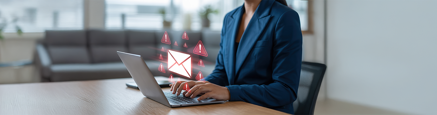Eine Frau sitzt an einem Laptop, über dem sich ein E-Mail-Bedrohungssymbol befindet