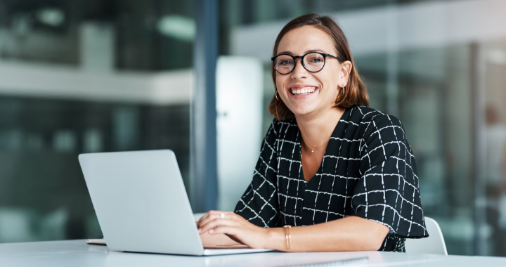 Lächelnde Frau arbeitet an einem Laptop.