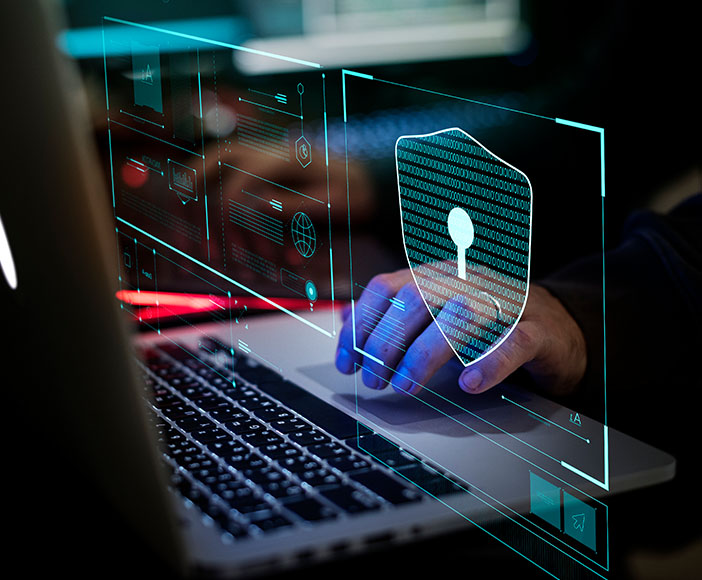 Person working on laptop with digital shield icon representing cybersecurity and data protection