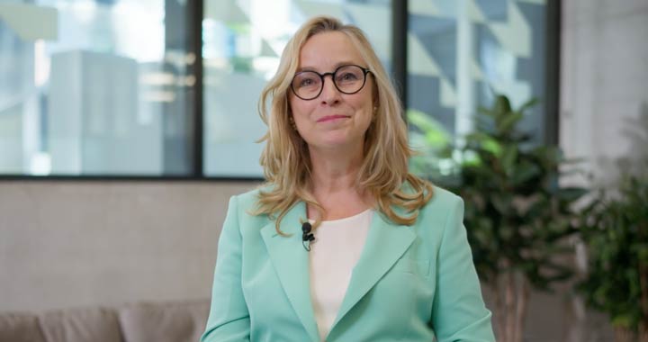 Frau in Business-Outfit mit Mikrofon in moderner Büroumgebung bei Präsentation oder Interview