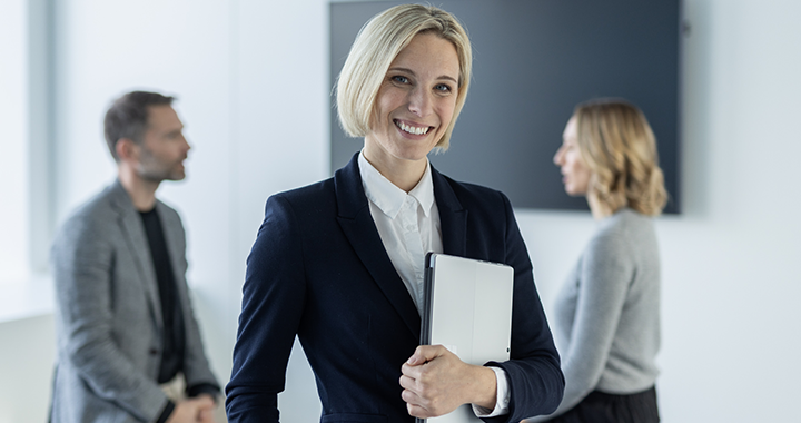 Eine glückliche Frau, die in einem Büro einen Laptop in den Händen hält.