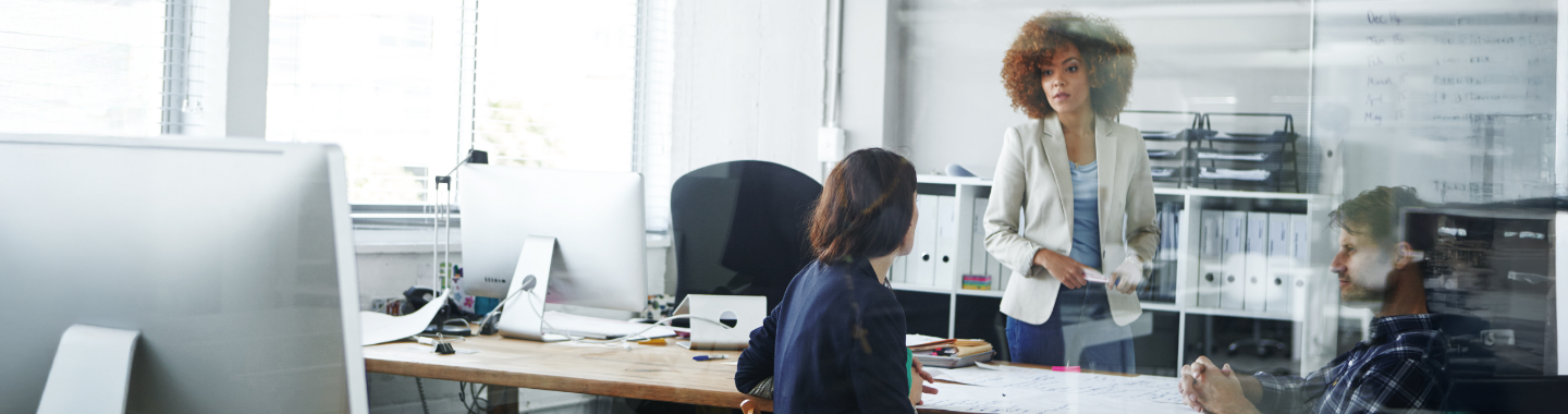 Drei Personen unterhalten sich in einem Büro.