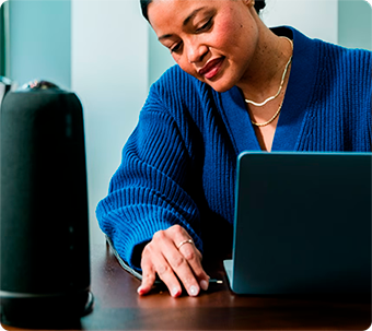 Person working focused on laptop while interacting with an Owl Labs device on the table in a modern setting