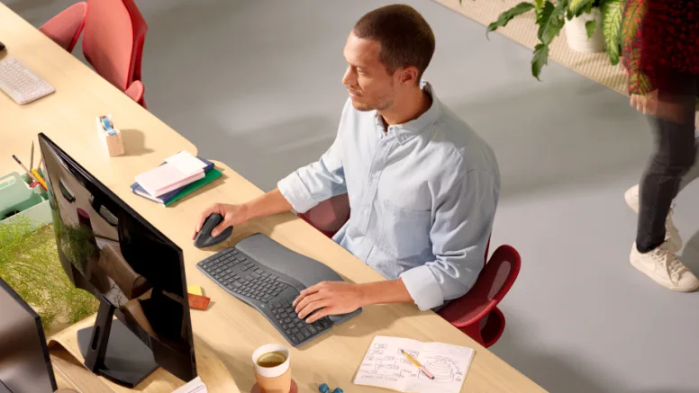 Person working focused at computer in modern office with desk and plants in the background