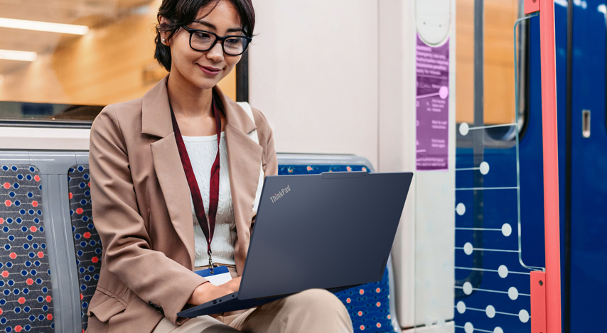 Eine Mitarbeiterin sitzt im Zug und arbeitet am Notebook