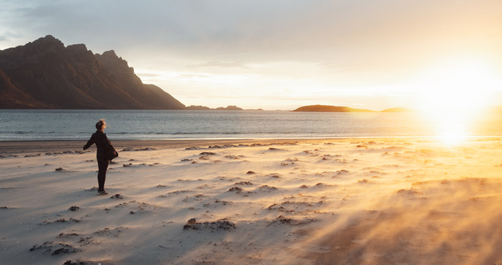 Person steht am Strand im Sonnenuntergang