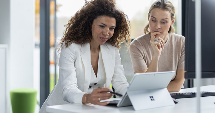 Glückliche Frauen, die an einem Microsoft Surface Tablet arbeiten