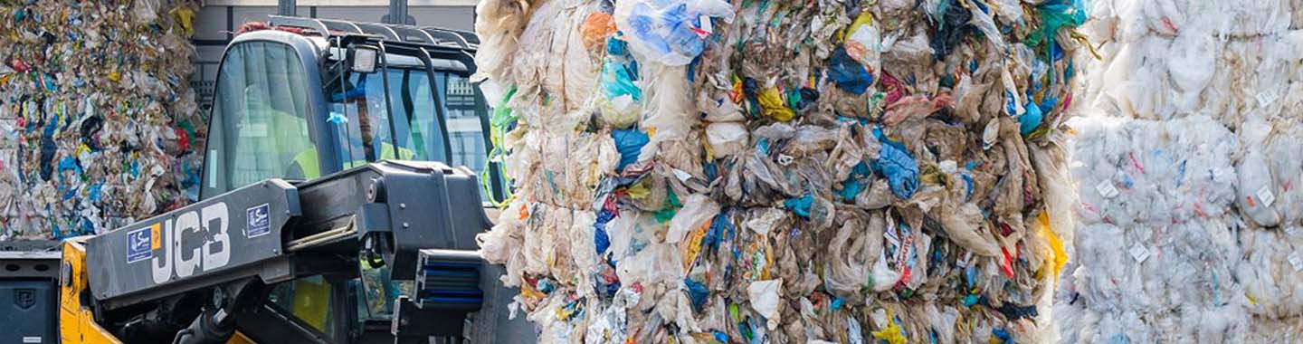 Das Bild zeigt wie ein Bagger Müll bewegt auf einer Mülldeponie