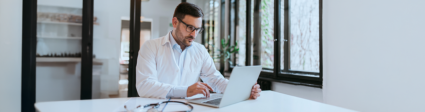 Ein Arzt arbeitet in einem Krankenhaus an einem Laptop.