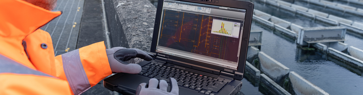 Person mit Panasonic Toughbook im Regen bei Nacht