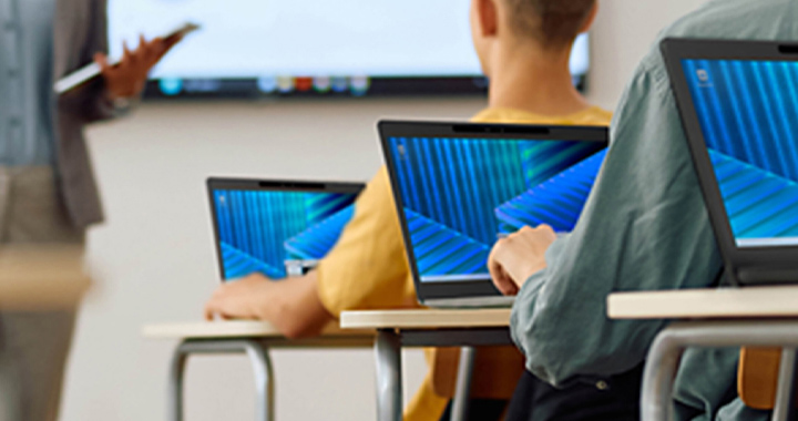 People in a classroom setting using laptops during a presentation for digital knowledge sharing