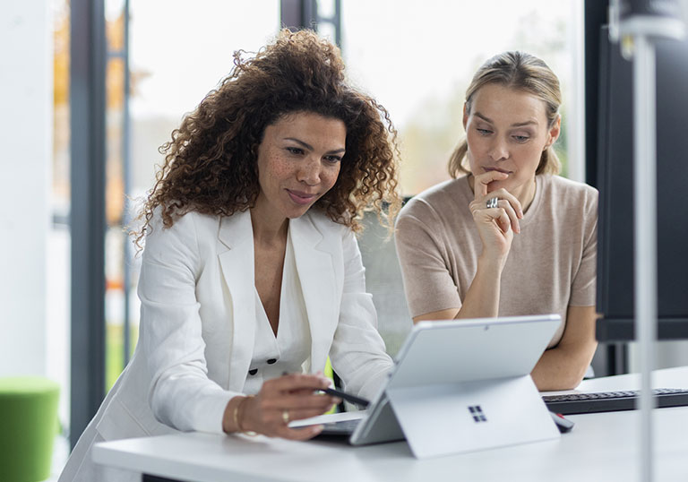 Glückliche Frauen, die an einem Microsoft Surface Tablet arbeiten