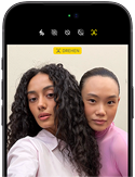 Two women taking a selfie with portrait mode activated on a smartphone