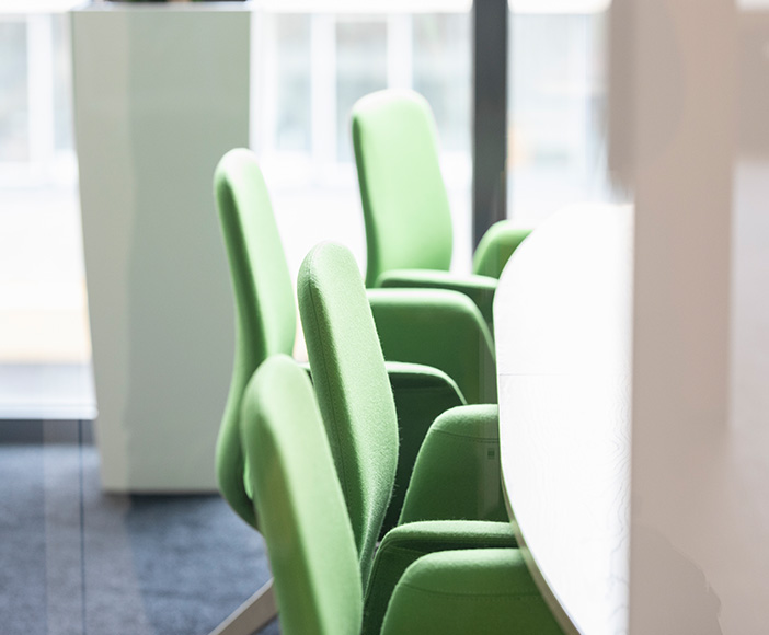 Empty green office chairs around a white conference table in a modern meeting room