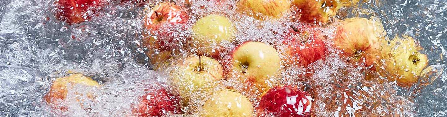 Red and yellow apples being washed in a water bath