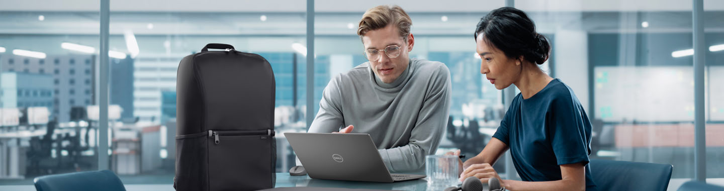 Mann und Frau sitzen an einem Bürotisch und schauen auf ein Dell-Notebook.
