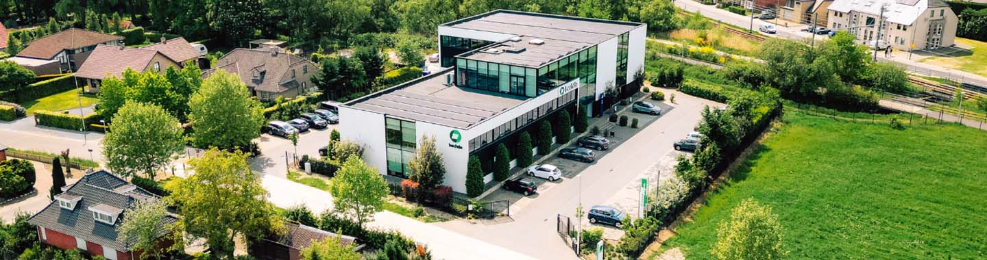 Modern office building with parking spaces in green surroundings on a sunny day