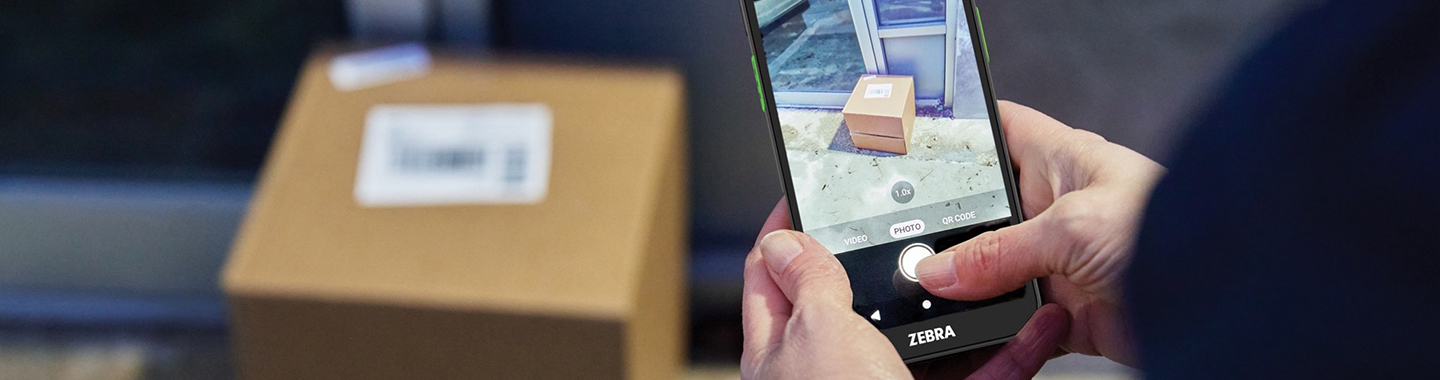 Main Banner Person photographing a package indoors with a Zebra Terminal 