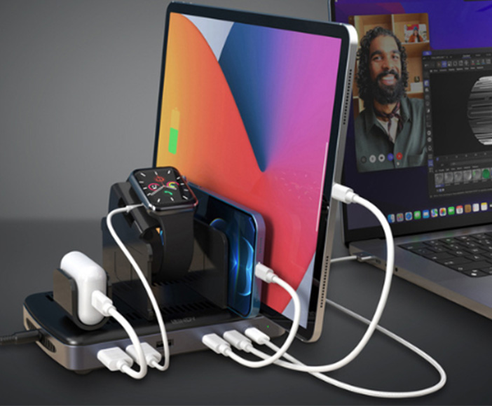 Mehrfach-Ladestation mit Tablet, Smartphone, Smartwatch und kabellosen Kopfhörern neben Laptop im Homeoffice