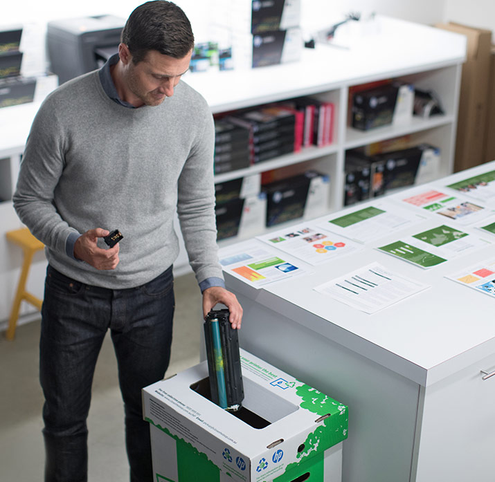 Mann gibt Kartusche in Recyclingtonne