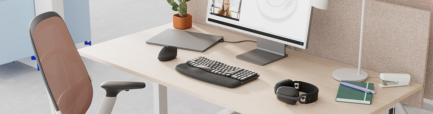 Modern workspace with height-adjustable desk and video conference displayed on the monitor