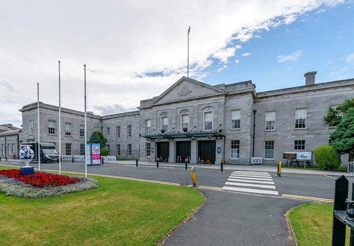 Historic government building with classical architecture and well-maintained front garden on a cloudy day