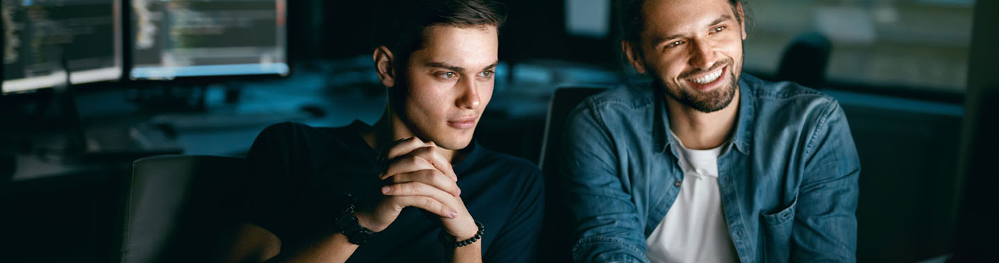 Two men sitting next to each other in an office