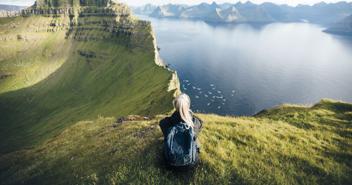 Person sitzt auf einem Bergplateau