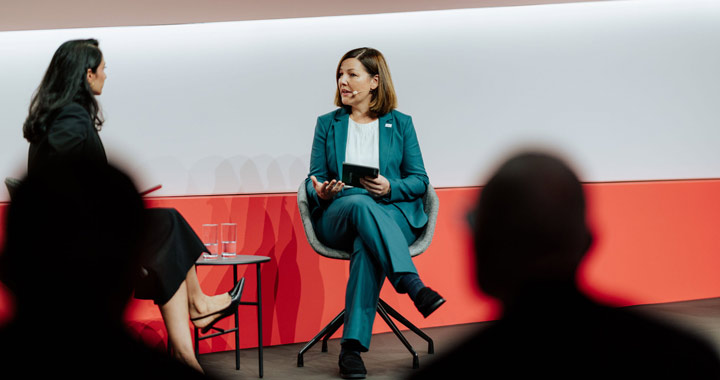 Zwei Personen im Gespräch auf einer Bühne bei einer moderierten Diskussion vor Publikum