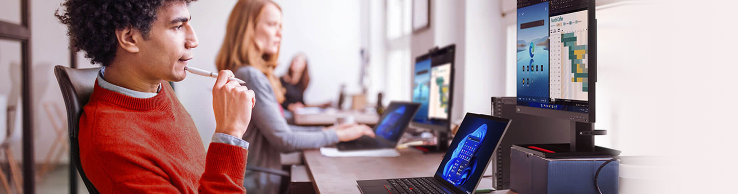Mehrere Mitarbeiter arbeiten am Schreibtisch mit Lenovo Notebooks und Monitoren.