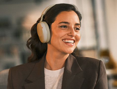 Woman wearing headphones smiling and participating in a virtual meeting in a modern work environment