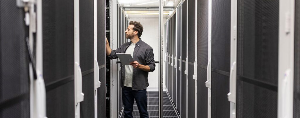 Techniker überprüft Server in einem modernen Rechenzentrum mit Tablet zur Systemkontrolle