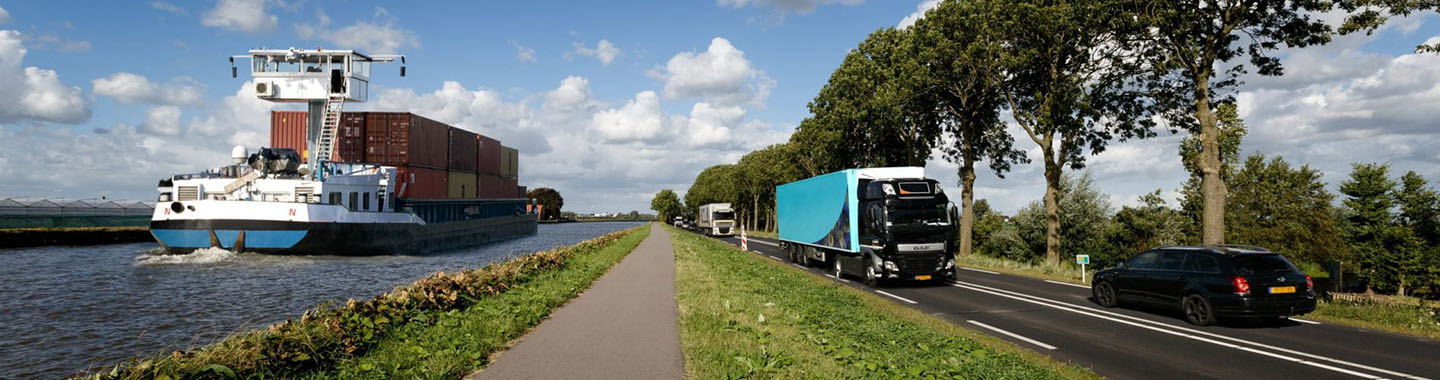 Cargo ship on a river next to a road