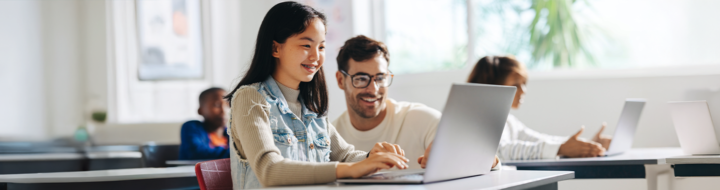 Der Lehrer hilft den Schülern, den Unterrichtsstoff auf dem Laptop zu verstehen.