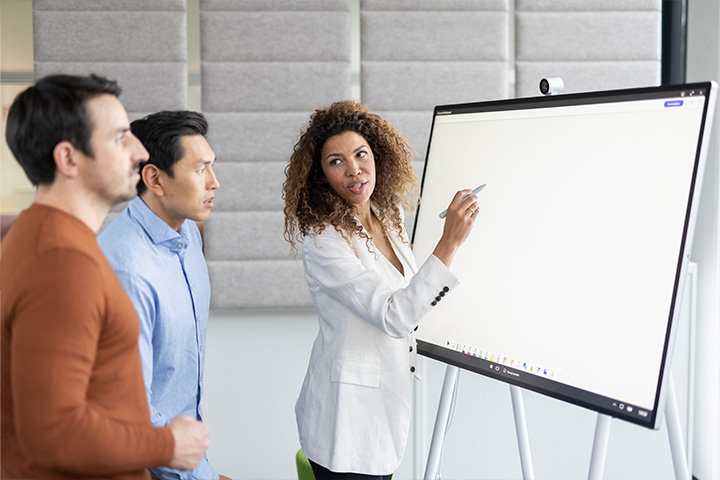 3 leute diskutieren den Inhalt einer digitalen Tafel