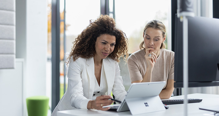 Two women consulting a tablet.