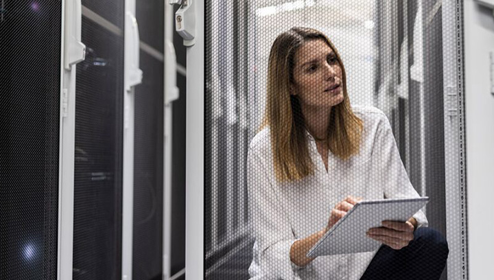Frau arbeitet an einem Tablet in einem Serverraum